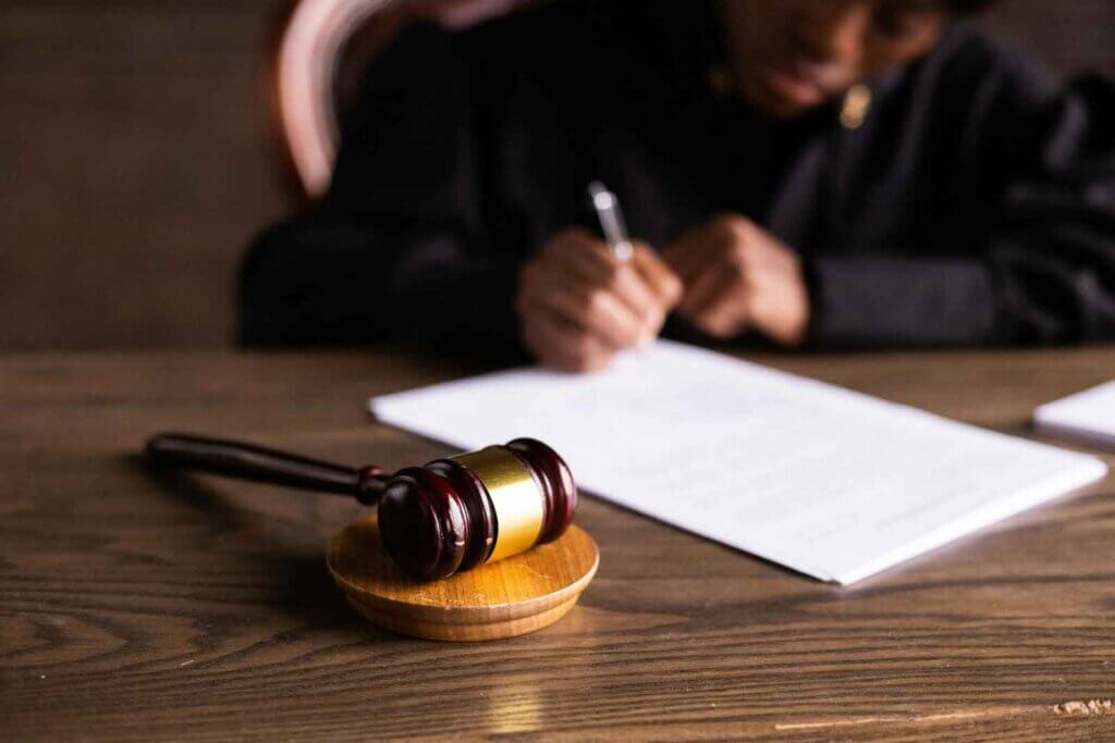 judge sitting at desk signing papers with a gavel in the foreground