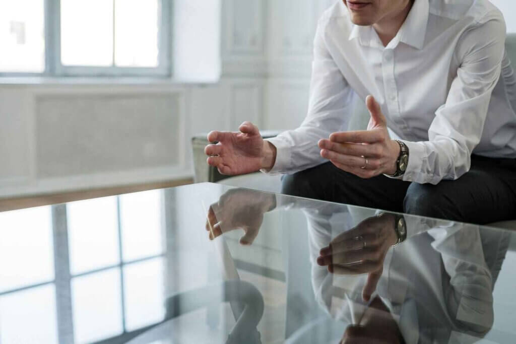 well dressed man sitting on a couch leaning over a glass coffee table